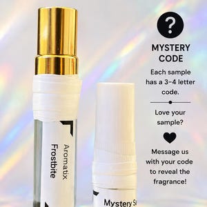 Op de afbeelding: Twee doorzichtige glazen parfumflesjes met witte etiketten. E&eacute;n flesje heeft een gouden dop en een etiket met de tekst Frostbite Aromatix. Het andere is een proefflesje van 1 ml met het label Mystery Sa Boe. De tekst bevat informatie over gratis samples, mysterieuze codes en de lekvrije verpakking.