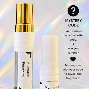 May include: Two clear glass fragrance vials with white labels. One vial has a gold cap and a label reading Frostbite Aromatix. The other is a 1ml sample vial labeled Mystery Sa Boe. Text includes Orders over $12 receive a free mystery sample, all samples are leak-proof wrapped, mystery code, and wrapped tight. Delivered right.