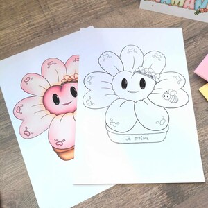 May include: Two flower-shaped art prints. One is colored in shades of pink, the other is a black and white line drawing. The flower has a smiling face, a small crown, and a bee. The words "JE T'AIME" are written on the pot.