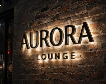 May include: A wall-mounted sign featuring the words AURORA LOUNGE in bold, dark, three-dimensional lettering. The letters are backlit, casting a warm, glowing light onto the textured, dark brown brick wall surface behind the signage.