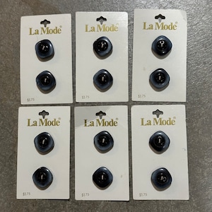 May include: Six packs of La Mode brand buttons. Each pack contains two dark gray, square-shaped buttons with a lighter gray swirl pattern. The buttons are on white cards with the brand name and price printed on them.