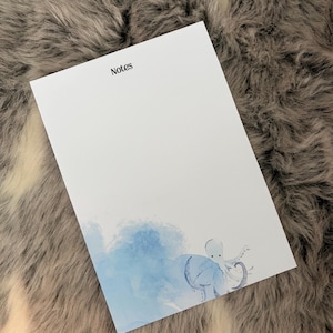 May include: A white rectangular notepad with the word Notes printed in black at the top. The bottom section features a light blue watercolor wash design with a small, detailed illustration of an octopus emerging from the blue paint.