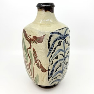 May include: A ceramic vase with a cream-colored base featuring hand-painted botanical motifs. The design includes brown and green floral elements on one side and a vertical pattern of blue and black fern-like leaves on the other, with a dark rim.