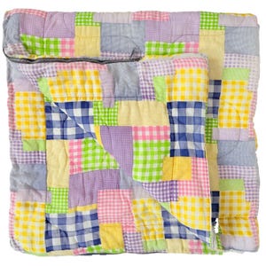 May include: A square quilted sleeping bag featuring a patchwork pattern of gingham squares in yellow, lime green, lavender, pink, and navy blue. The fabric has a small-scale checkered print throughout, and a metal zipper runs along the top edge.