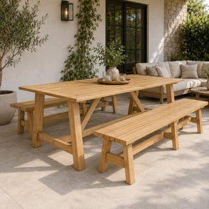 May include: A rectangular light brown wooden dining table with two matching backless benches. The table features a sturdy trestle base with angled legs and horizontal support beams. The set is constructed from smooth, natural-toned wood planks.