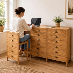 Op de afbeelding: Een bureau van licht hout met een grote kast met twaalf lades en een bijpassende stoel met vijf geïntegreerde lades, beide voorzien van donkere metalen komgrepen, die samen een functionele werkplek met laptop vormen.