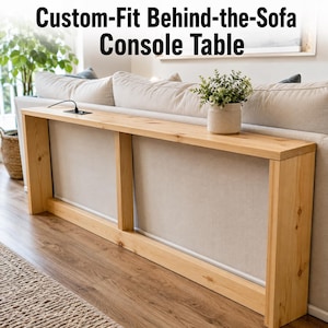 Puede incluir: Una mesa consola de madera clara, larga y estrecha, con una superficie rectangular y dos soportes laterales verticales. La mesa cuenta con una toma de corriente negra insertada en la parte superior. El texto "Custom-Fit Behind-the-Sofa Console Table" es visible.
