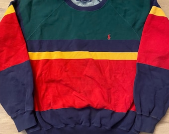 May include: A vintage crew neck sweatshirt with a color block design. The top section is green, with a yellow and navy blue stripe across the chest. The sleeves are red with navy blue cuffs. A small red polo logo is on the chest.