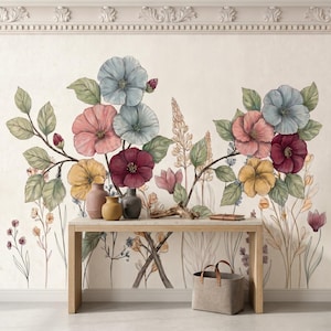May include: A wall mural featuring a botanical illustration of large blue, pink, yellow, and deep red flowers with green leaves and stems. A light-colored wooden console table sits in front of the wall, holding two ceramic vases and a small wooden object.