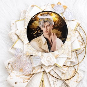 May include: A decorative badge with a portrait of a person with silver hair and a halo, set against gold roses. The badge is surrounded by white and gold ribbons, with gold accents and decorative embellishments.
