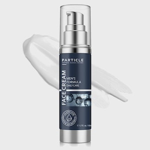 Op de afbeelding: Een zilveren en marineblauwe gezichtscr&egrave;mefles met een pompdosser. Het etiket luidt "Particle Aesthetic Science for Men" en "Men's Formula Daily Care". De fles bevat 50 ml product. Een witte cr&egrave;me streep op de achtergrond.