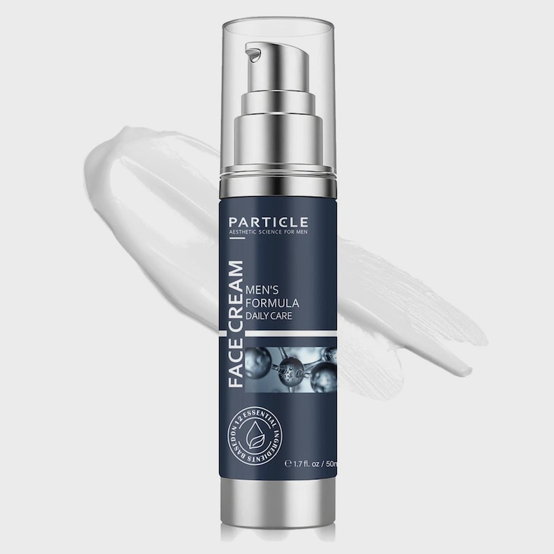 Op de afbeelding: Een zilveren en marineblauwe gezichtscr&egrave;mefles met een pompdosser. Het etiket luidt "Particle Aesthetic Science for Men" en "Men's Formula Daily Care". De fles bevat 50 ml product. Een witte cr&egrave;me streep op de achtergrond.