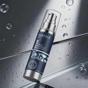 Op de afbeelding: Een zilveren en marineblauwe Particle gezichtscr&egrave;mefles met een doorzichtige pomptop. Het etiket leest "FACE CREAM", "MEN'S FORMULA DAILY CARE" en "1,7 fl oz / 50 ml". De achtergrond is een reflecterend oppervlak met waterdruppels.