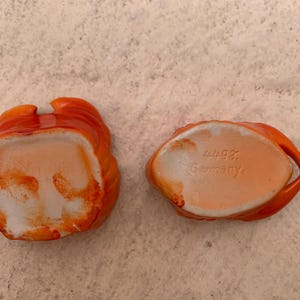 May include: Two orange ceramic bowls with white interiors. The bowl on the right has the text "W.98 Germany" on the bottom.