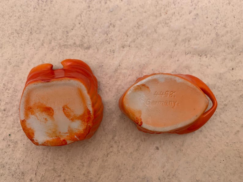 May include: Two orange ceramic bowls with white interiors. The bowl on the right has the text "W.98 Germany" on the bottom.