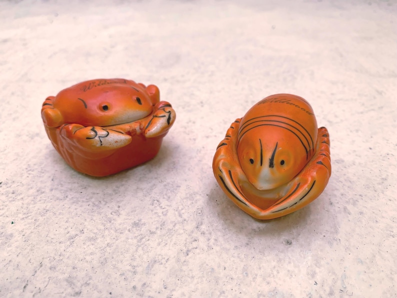 May include: Two ceramic figurines of a crab and a lobster. Both are orange with black details and have a glazed finish.