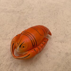 May include: Orange and black ceramic lobster figurine with the word "Atlantic City" written on the top.