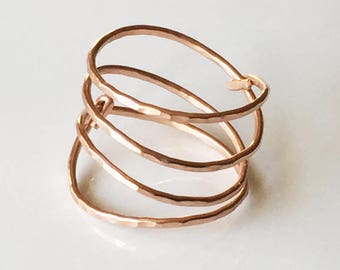 May include: A rose gold hammered metal ring with four bands stacked on top of each other.