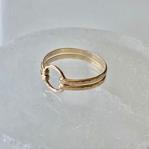 May include: A gold ring with a hammered finish and a circle design. The ring is double-banded.