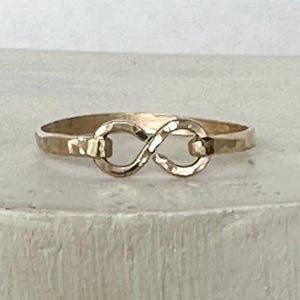 May include: A gold infinity ring with a hammered finish. The ring is simple and elegant, making it a perfect choice for everyday wear.
