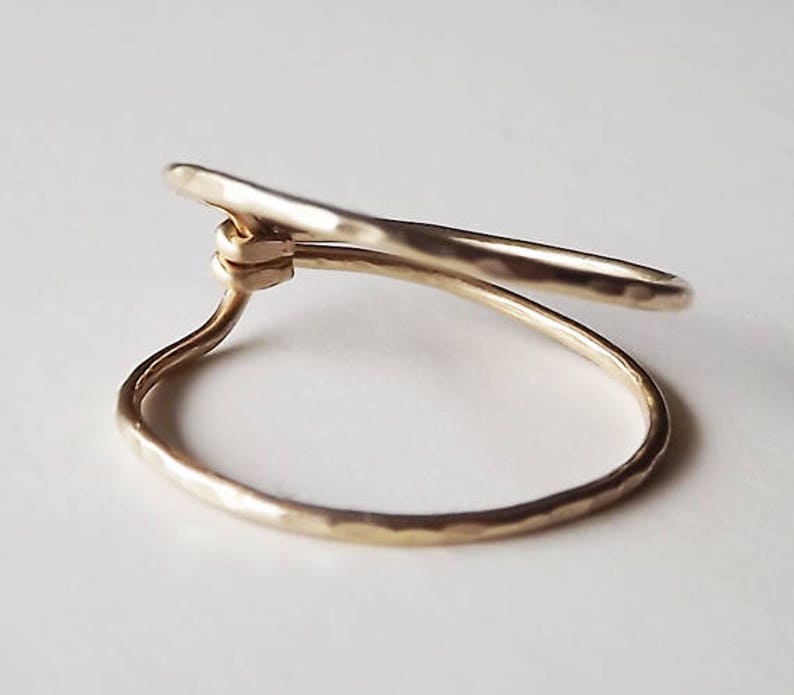May include: A gold-toned ring with a hammered finish, featuring a unique twisted design.
