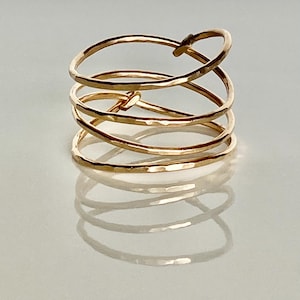 May include: A gold ring with a hammered finish, made of five intertwined bands.