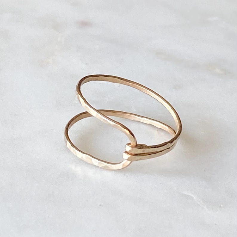 May include: A gold-toned double ring with a hammered finish. The ring is open and can be adjusted to fit different finger sizes.