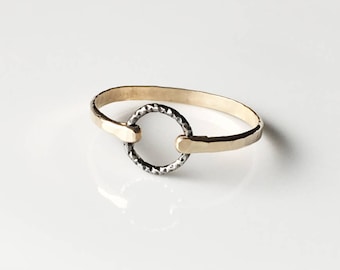 May include: A gold ring with a textured, black circle in the center.