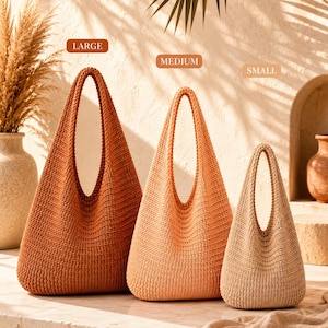 Può includere: Tre borse hobo di dimensioni e colori graduati, etichettate LARGE, MEDIUM e SMALL. La borsa grande è color ruggine scuro, la media è arancione chiaro e la piccola è beige. Ogni borsa presenta una trama lavorata a maglia con un manico.