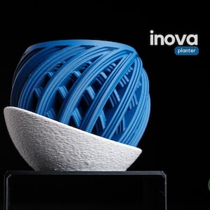 Può includere: Un'aiuola moderna con un design blu, sferico, a forma di reticolo, appoggiata su una base bianca, strutturata e curva. Le parole "inova" e "planter" sono visualizzate in testo bianco e blu. Lo sfondo è nero.