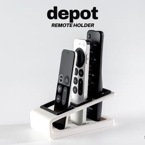 May include: A white remote holder with three remotes. The remotes are black and white. The text "depot REMOTE HOLDER" is at the top of the image. The design is by st3rn.