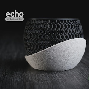 May include: A black and white orchid planter labeled echo orchid planter and h3liø design. The upper section features a black, intricate, repeating wave-like lattice pattern, while the lower base is a solid, textured, off-white curved shell.