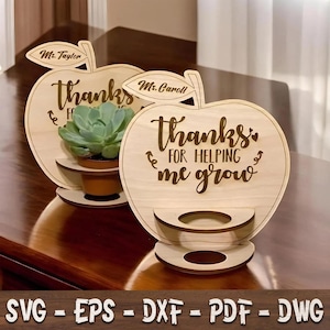 May include: Two light-coloured wooden apple-shaped plaques with a circular cutout for a small plant pot. The plaques feature the engraved text "thanks FOR HELPING me grow" and a leaf with names "Ms. Taylor" and "Ms. Caroll" at the top.