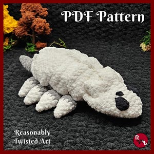 May include: A white and gray crocheted plush toy shaped like a pill bug or isopod with multiple legs and dark spots on its head. The text PDF Pattern and Reasonably Twisted Art are visible. The plush has a soft, fuzzy texture and a segmented body.