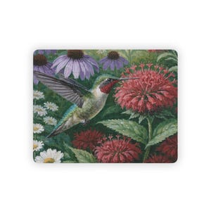 May include: A rectangular jigsaw puzzle featuring a vibrant painting of a hummingbird with iridescent green feathers and a red throat hovering near large, bright red bee balm flowers, surrounded by purple coneflowers and small white daisies.