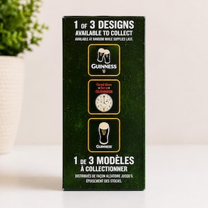 May include: A dark green box with the Guinness logo and text. The box displays three different designs available to collect. The text reads "1 of 3 designs available to collect" and "available at random while supplies last."