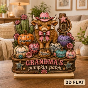 Könnte beinhalten: Ein dekoratives Holzdisplay mit einem flauschigen Hochlandrind, das einen rosa Cowboyhut und eine Schleife trägt, umgeben von Kürbissen mit den Namen Benjamin, Charlotte, Elijah, Matthew, Theodore, Samuel, Isabella und Avery sowie dem Text Grandma's pumpkin patch.
