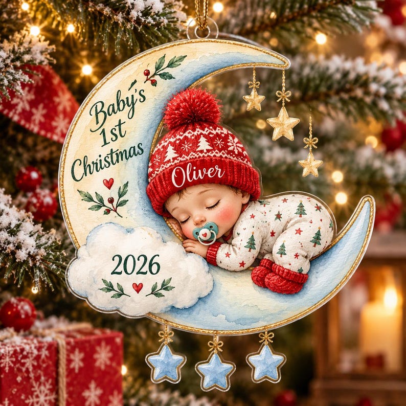 K&ouml;nnte beinhalten: Ein weihnachtlicher Baumschmuck in Mondsichelform mit einem schlafenden Baby in roter Strickm&uuml;tze und gemustertem Schlafanzug. Das Ornament zeigt den Text Baby's 1st Christmas, den Namen Oliver und das Jahr 2026, verziert mit goldenen und blauen Sternen.