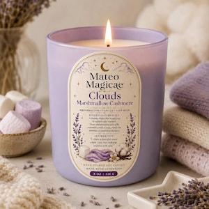 Peut inclure: Une bougie lilas allumée avec le texte "Mateo Magicae Clouds Marshmallow Cashmere." La bougie est entourée de guimauves, d'un plat en forme d'étoile avec de la lavande et d'un croissant de lune doré. La bougie est de 226 g.
