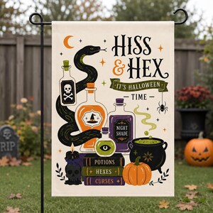 May include: A rectangular garden flag featuring a black snake, potion bottles, a cauldron, and a stack of books labeled Potions, Hexes, and Curses. The text reads Hiss & Hex It's Halloween Time. The design includes a skull, spider, and pumpkin.