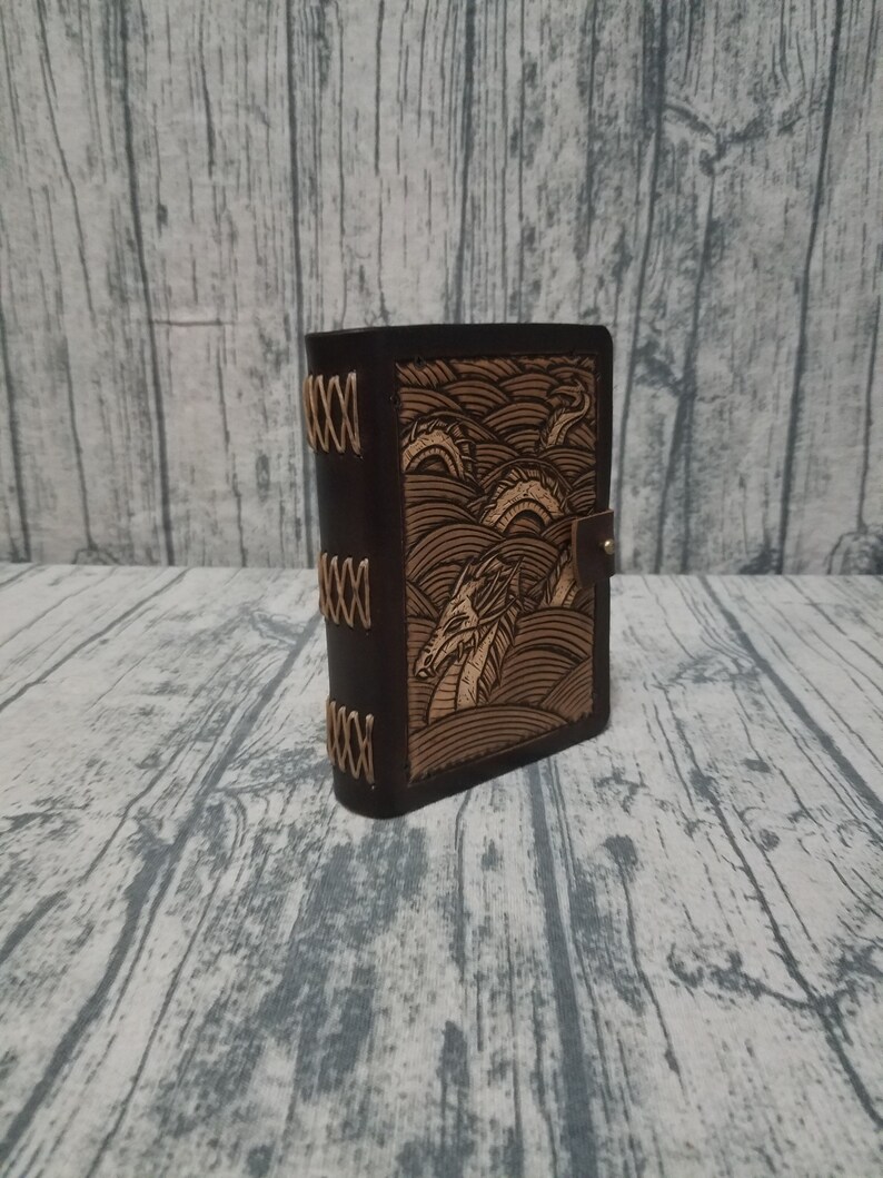Leather and wood adventure tome hollow book dice box with sea serpent loch ness carving on cover
