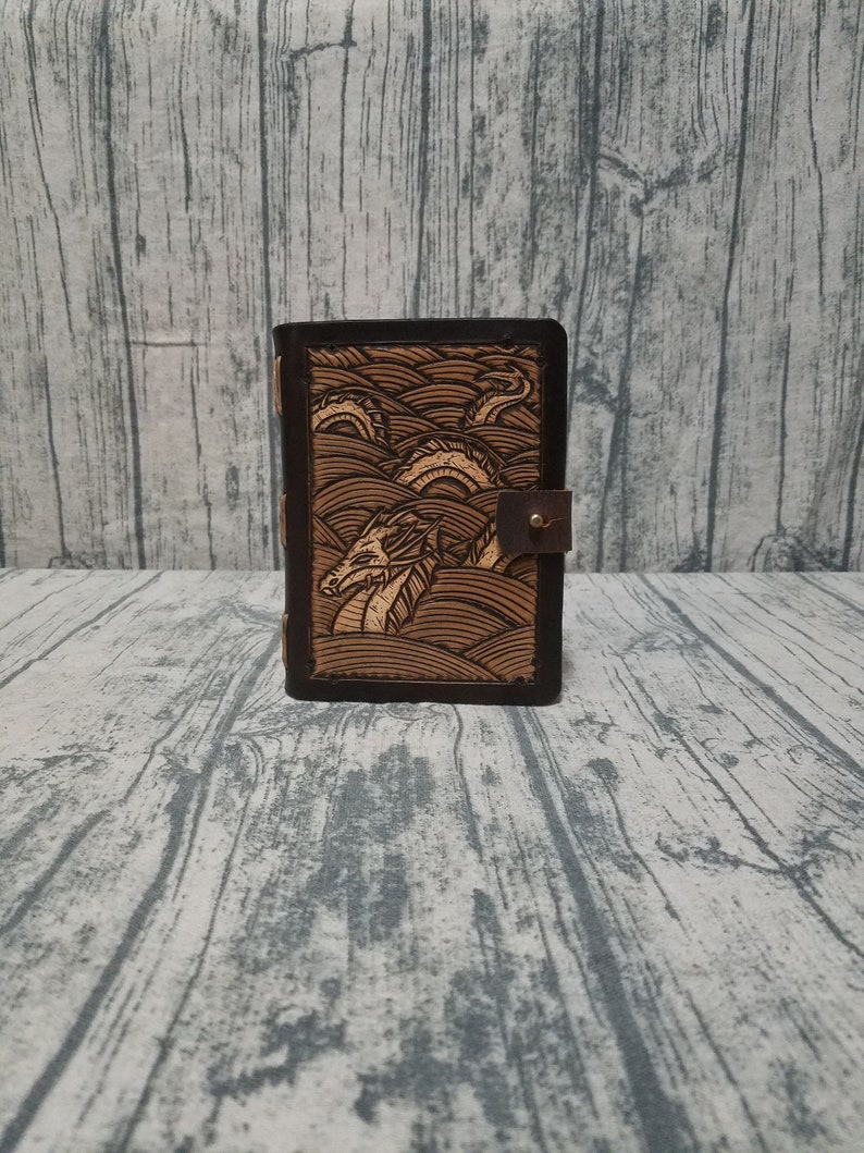 Leather and wood adventure tome hollow book dice box with sea serpent loch ness carving on cover