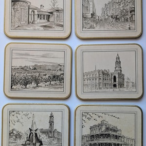 May include: A set of six rectangular coasters with rounded corners, each featuring a black and white ink sketch of an Adelaide landmark. The designs include Ayers House, Rundle Mall, a vineyard, the Town Hall, a fountain, and the Botanic Hotel.