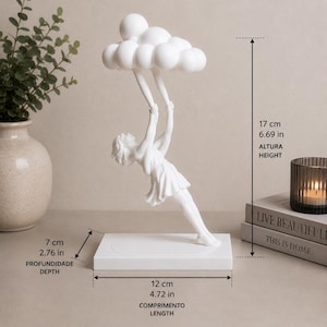 May include: A white sculpture of a figure suspended from a cloud, mounted on a rectangular base. The piece measures 6.69 inches in height, 4.72 inches in length, and 2.76 inches in depth, showing a figure reaching upward to hold a cloud formation.
