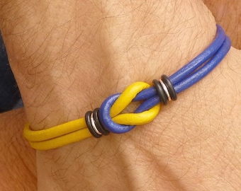 Pulsera de cuero azul y amarillo con nudo de eternidad y cierre magnético.