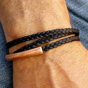 May include: A black leather braided bracelet with a copper clasp.