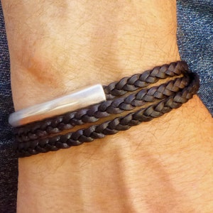 May include: A brown leather braided bracelet with a silver bar accent.