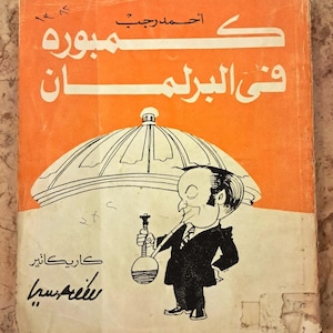 Peut inclure: Une couverture de livre avec un fond orange, du texte arabe en blanc et une illustration en noir et blanc représentant une personne en costume fumant une pipe à eau sous un dôme. La couverture est usée et comporte des chiffres manuscrits.