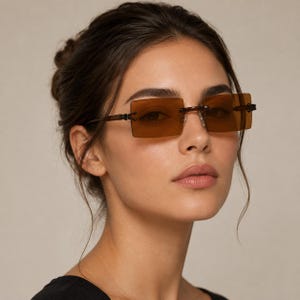 May include: Rimless rectangular sunglasses featuring translucent brown lenses and thin dark brown temples. The eyewear has a minimalist design with visible metal hinges connecting the lenses to the frame arms, providing a clear view of the eyes.