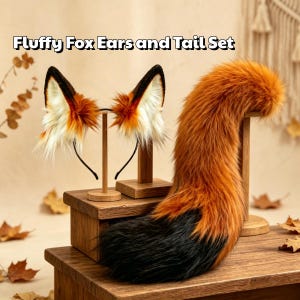 May include: A fluffy fox ears and tail set featuring orange, white, and black faux fur. The ears are attached to a thin black headband, and the long, bushy tail has a black tip. The text 'Fluffy Fox Ears and Tail Set' is visible above.